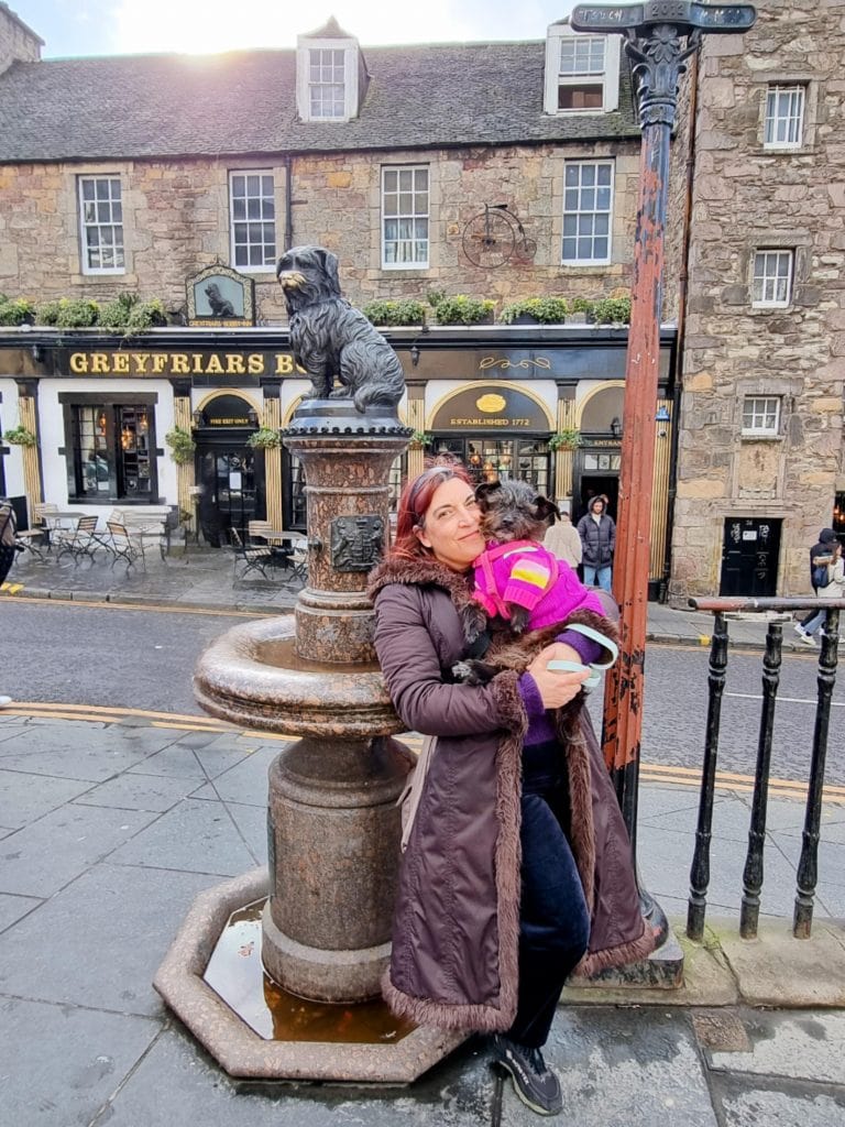 Sandra holding Cookie beside Greyfriars Bobby statue in Edinburgh.