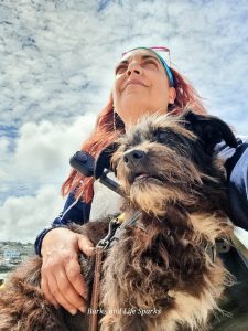 Sandra holding Cookie under a bright sky, showing the human-dog bond.